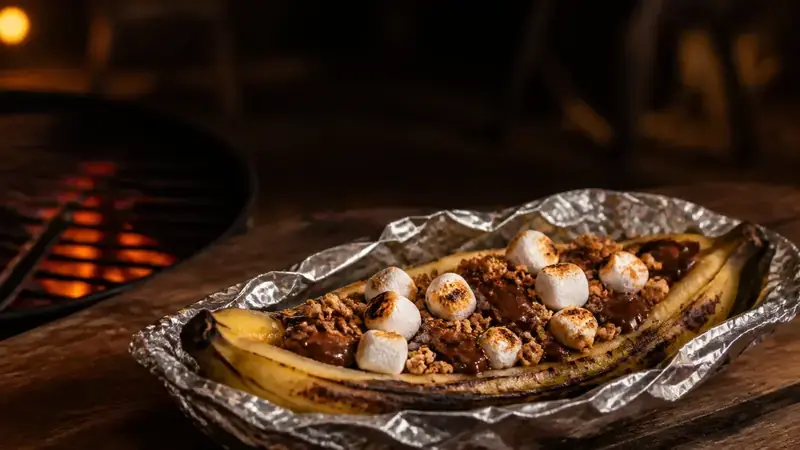 Gegrillte Banane vom Grill mit geschmolzener Schokolade, gerösteten Marshmallows und knusprigem Müsli.